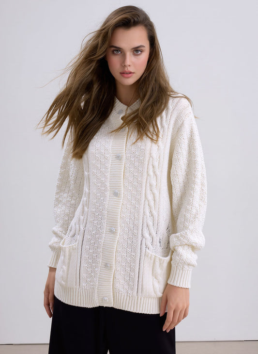 Woman wearing a cream chunky knit cardigan with button closure and front pockets